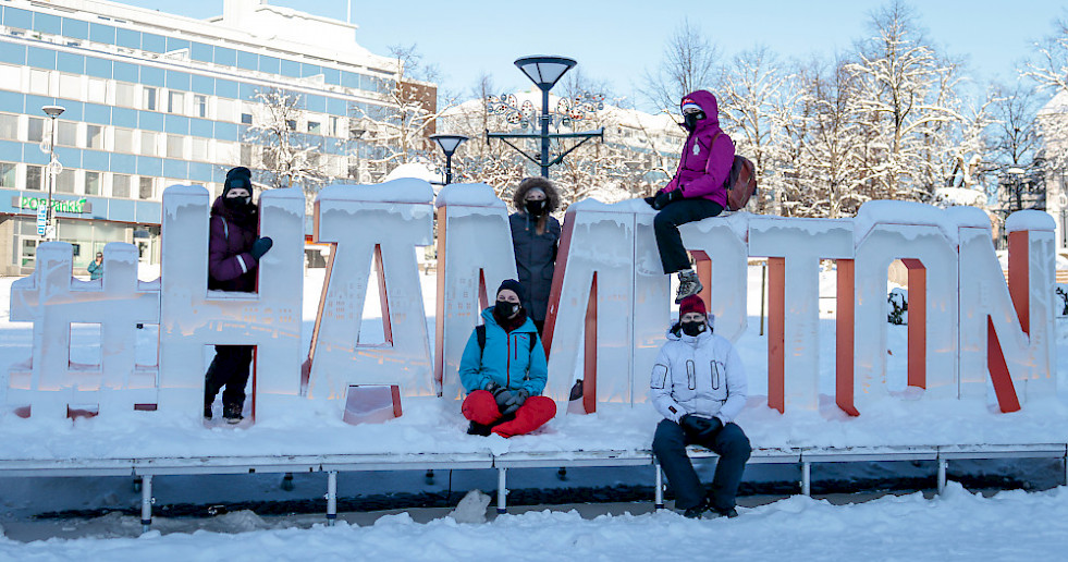 Hämeenlinnan etsivän nuorisotyön tiimi lumisen #Hämpton-merkin edessä.
