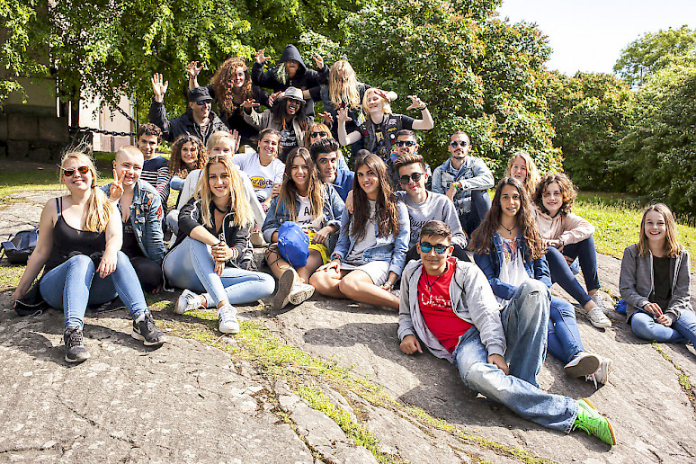 Nuorisovaihtoryhmä Suomesta ja Espanjasta istuu yhteiskuvassa kalliolla.